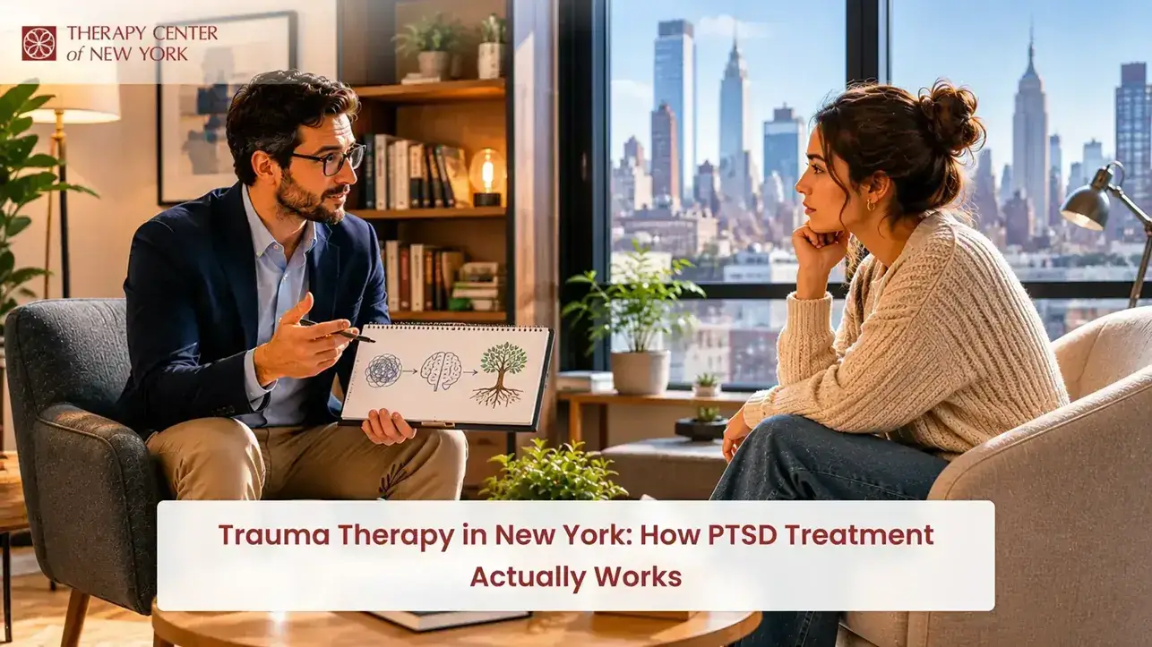Trauma therapist explaining PTSD treatment to a client during a counseling session in a New York office with city skyline views.